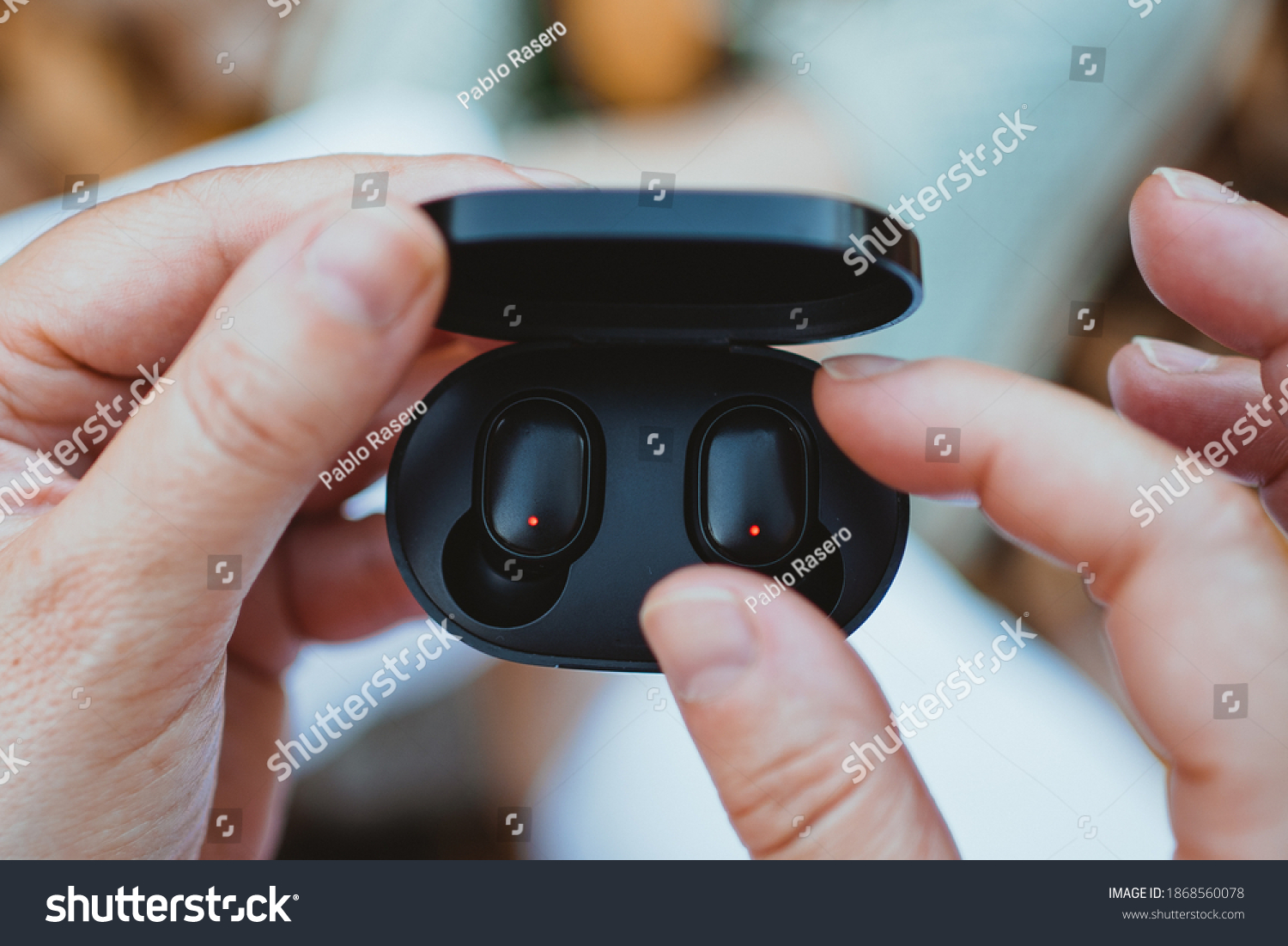 close-up of a woman taking out a wireless earbud from his charging box #1868560078