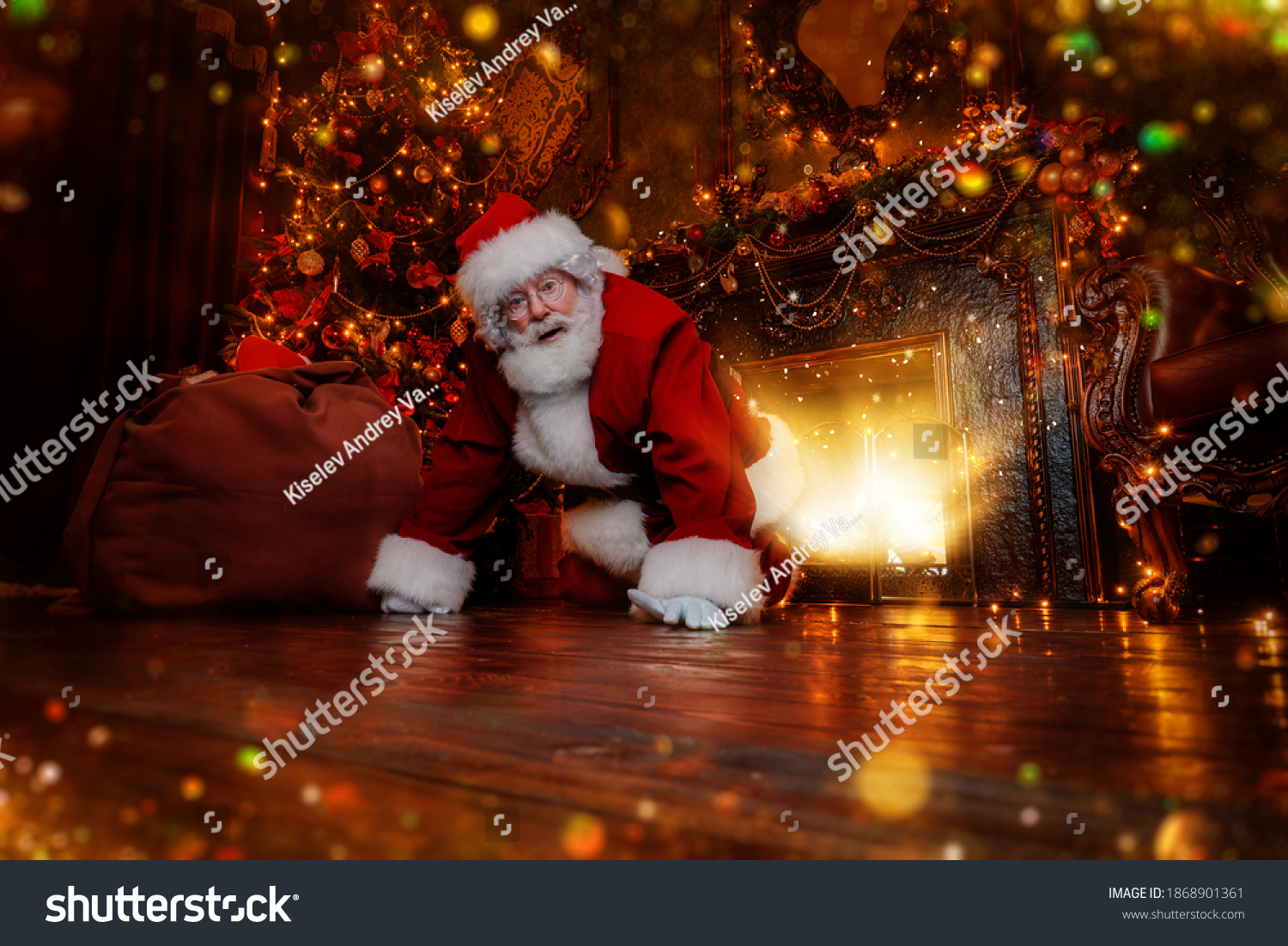 Jolly Santa Claus sneaked into the house through the fireplace with a bag of gifts. Beautiful home decoration. Merry Christmas and Happy New Year! #1868901361