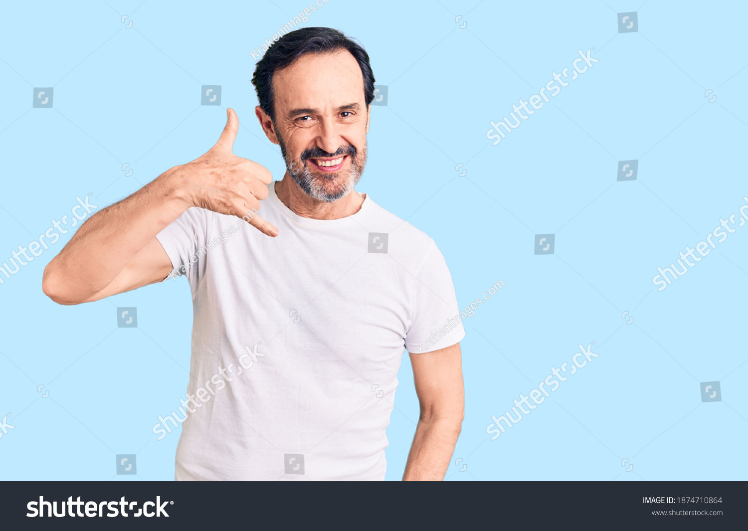 Middle age handsome man wearing casual t-shirt smiling doing phone gesture with hand and fingers like talking on the telephone. communicating concepts.  #1874710864