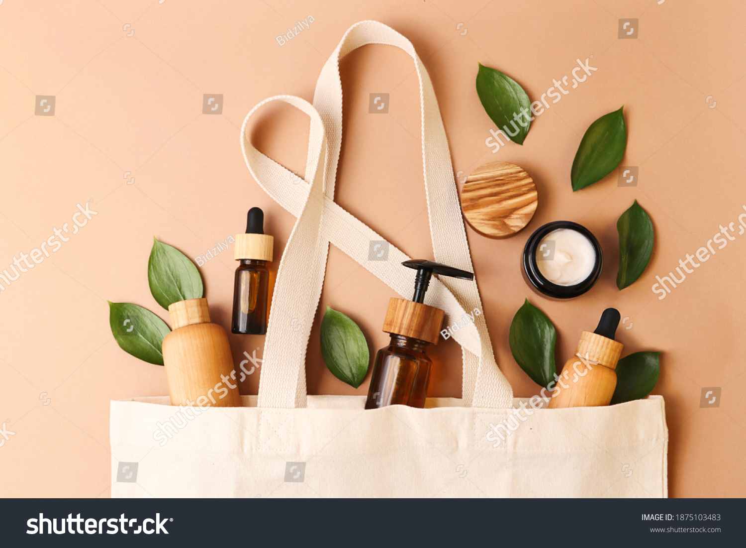 Open eco friendly cotton reusable bag with the different containers from the natural wood and brown glass.Fresh natural leafs around.Concept of organic,zero waste cosmetics.Woman bag with ac?essories. #1875103483