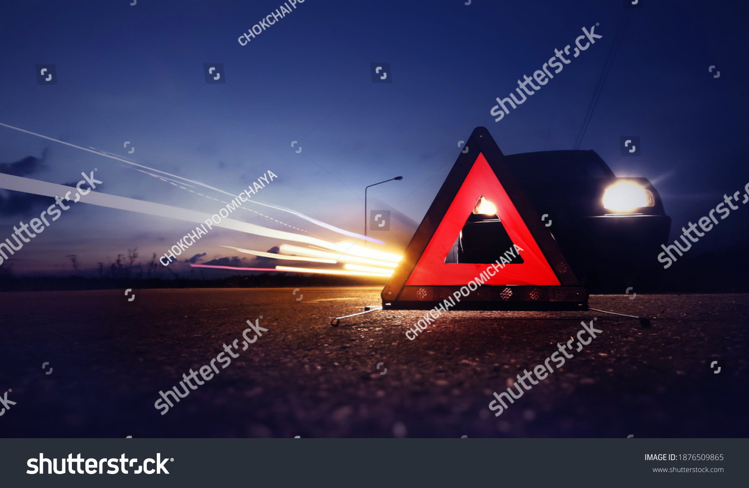 Red emergency stop sign (red triangle warning sign) with long-exposure of traffic light trails at nigh. #1876509865