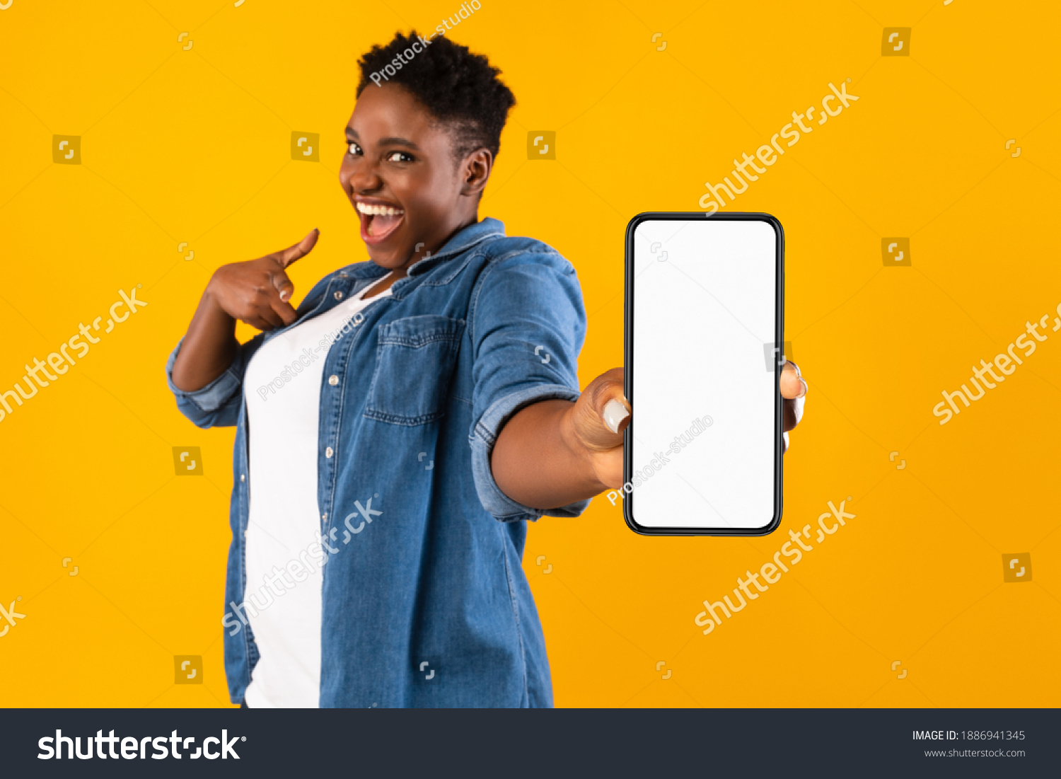 Mobile Application Ad. Excited African Woman Showing Phone Empty Screen Recommending App Standing Over Yellow Studio Background, Smiling To Camera. Cellphone Display Mockup, Check This Apps #1886941345