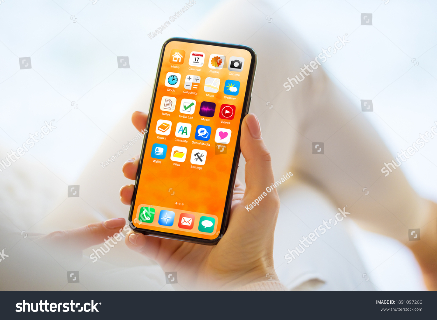 Woman using mobile phone with home screen opened showing different everyday app icons #1891097266