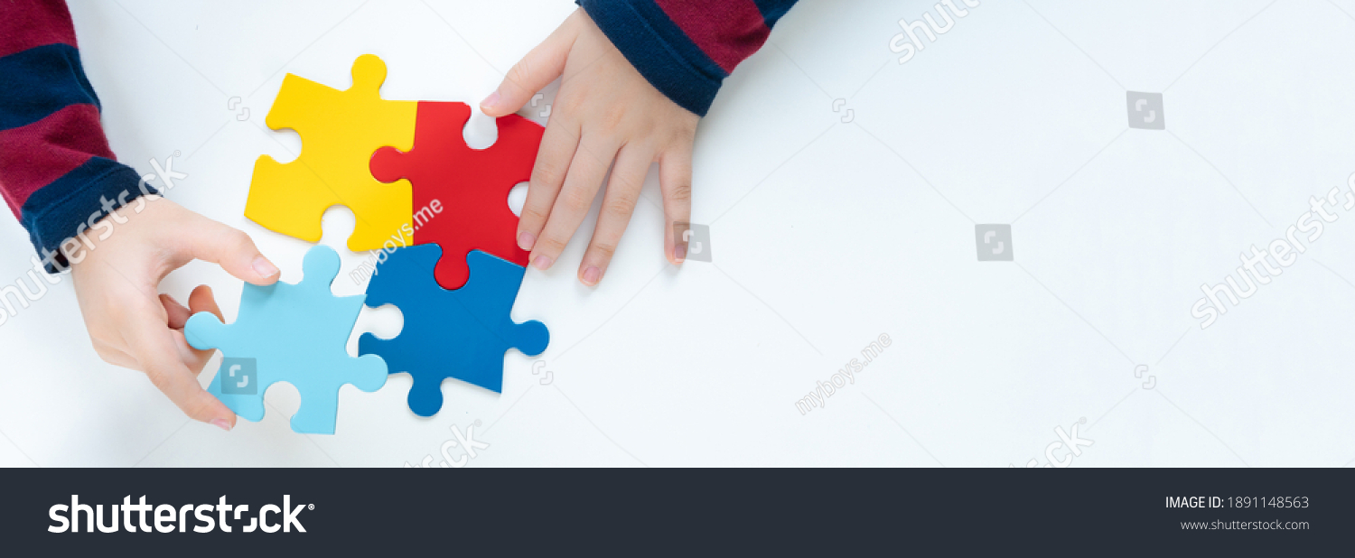Top view hands of a little child arranging color puzzle symbol of public awareness for autism spectrum disorder. World Autism Awareness Day, ASD, Caring, Speak out, Campaign, Togetherness. Banner. #1891148563