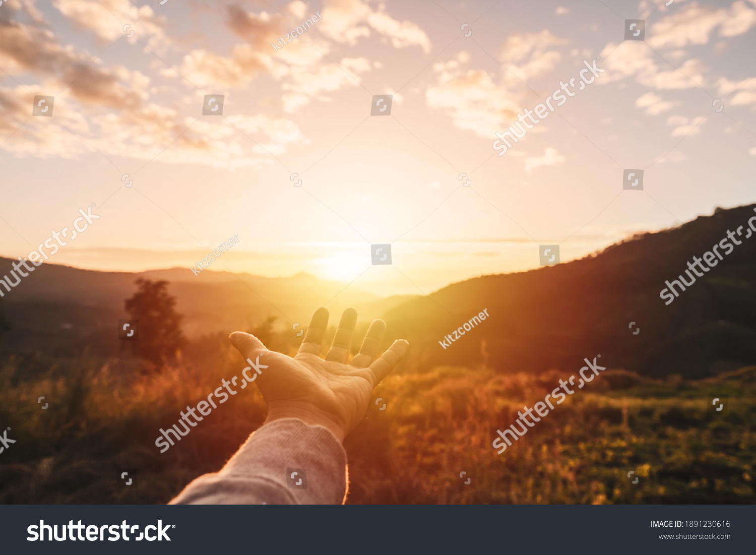 Young man hand reaching for the mountains during sunrise and beautiful landscape #1891230616