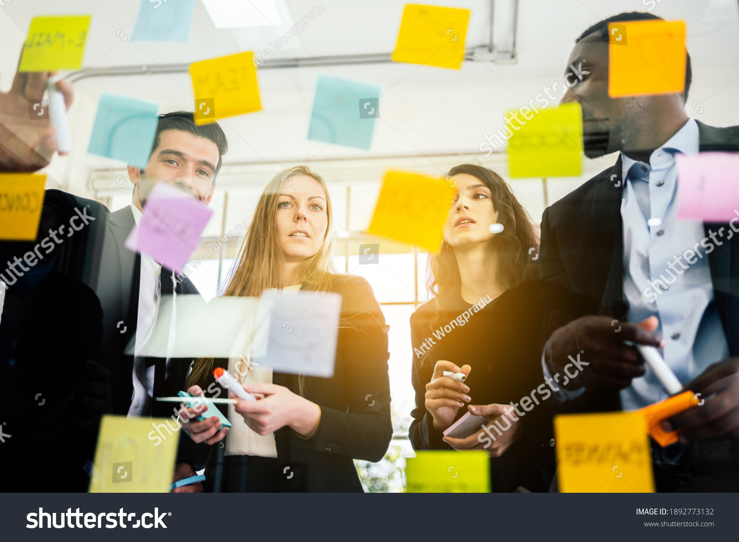 Group of successful business teamwork. Brainstorm meeting with colorful sticky paper note on glass wall for new ideas. Using agile methodology and do business. Brainstorming in a tech start-up office. #1892773132