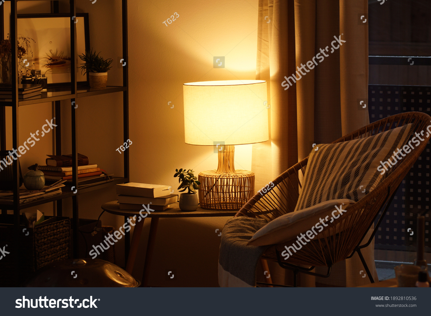 View of a cozy reader's corner with a table lamp spending warm light #1892810536