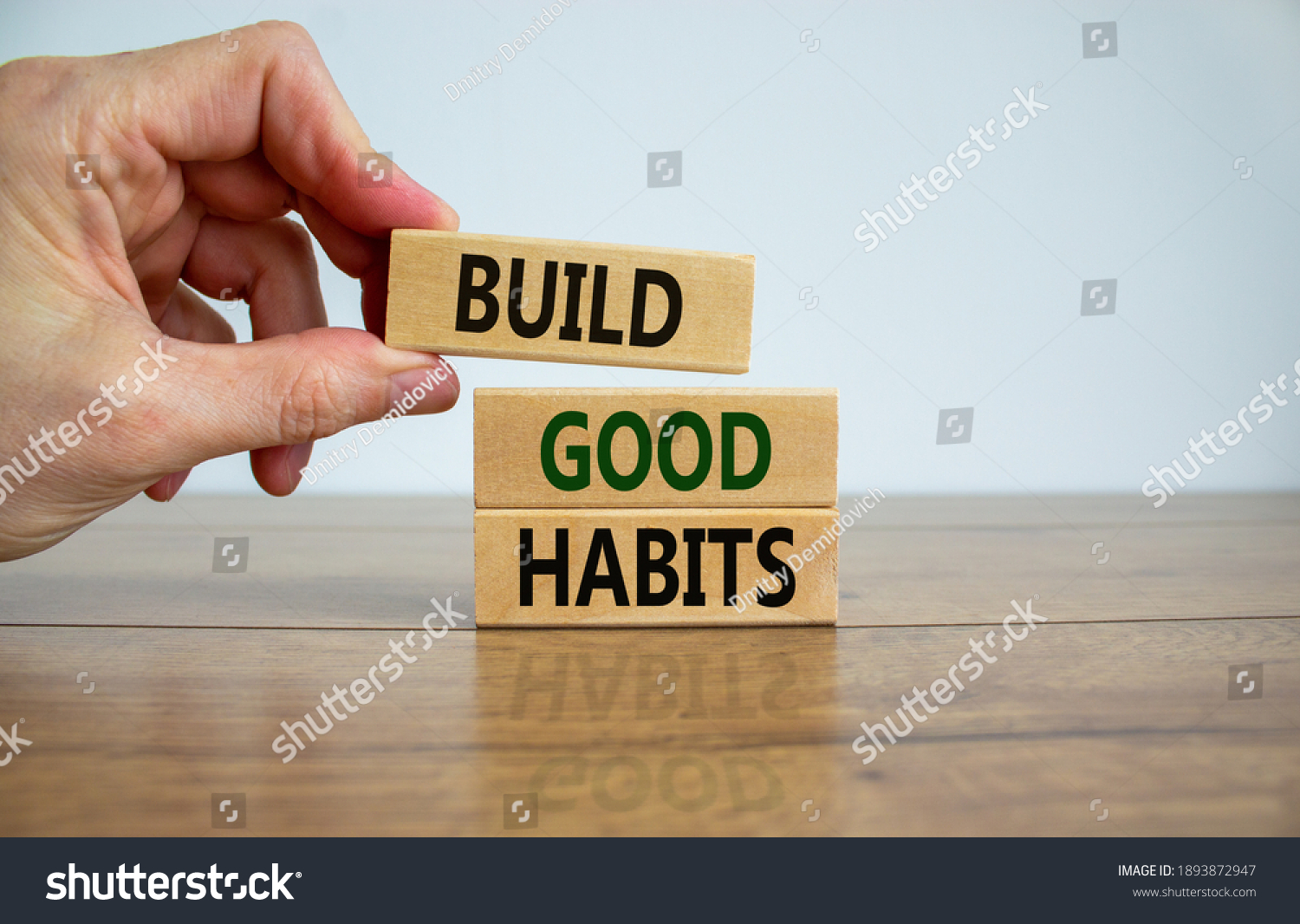 Build good habits symbol. Wooden blocks with words 'build good habits'. Male hand. Beautiful wooden table, white background, copy space. Business, psychological and build good habits concept. #1893872947
