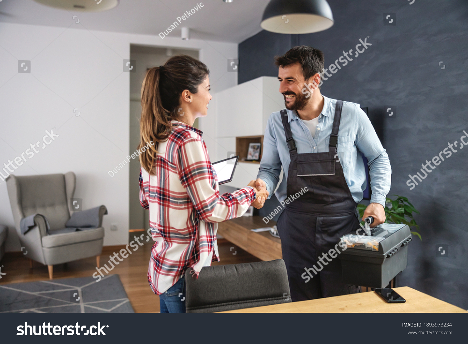 Happy woman shaking hands with repairman. Home interior. #1893973234
