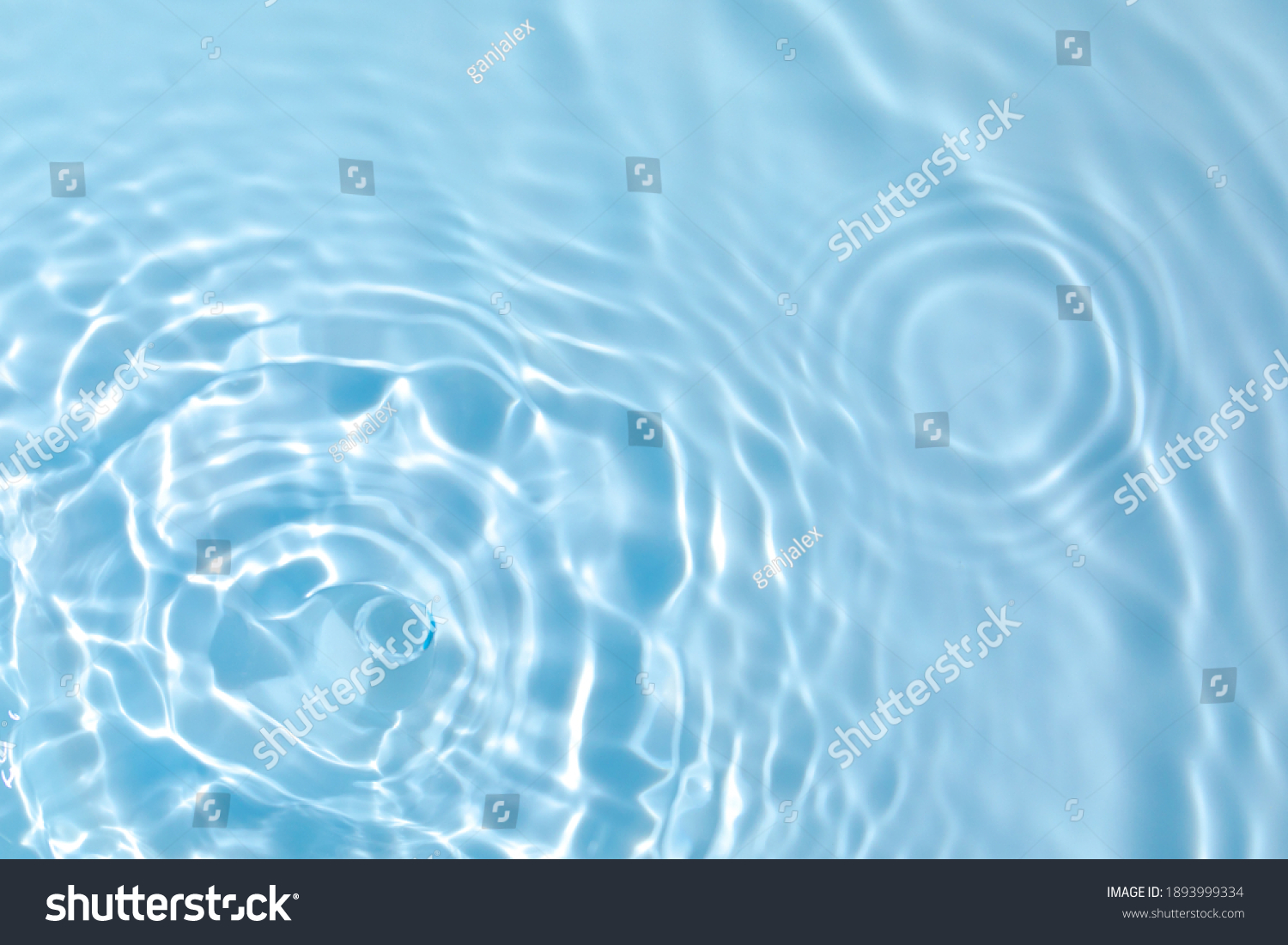 De-focused blurred transparent blue colored clear calm water surface texture with splashes and bubbles. Trendy abstract nature background. Water waves in sunlight with copy space. #1893999334