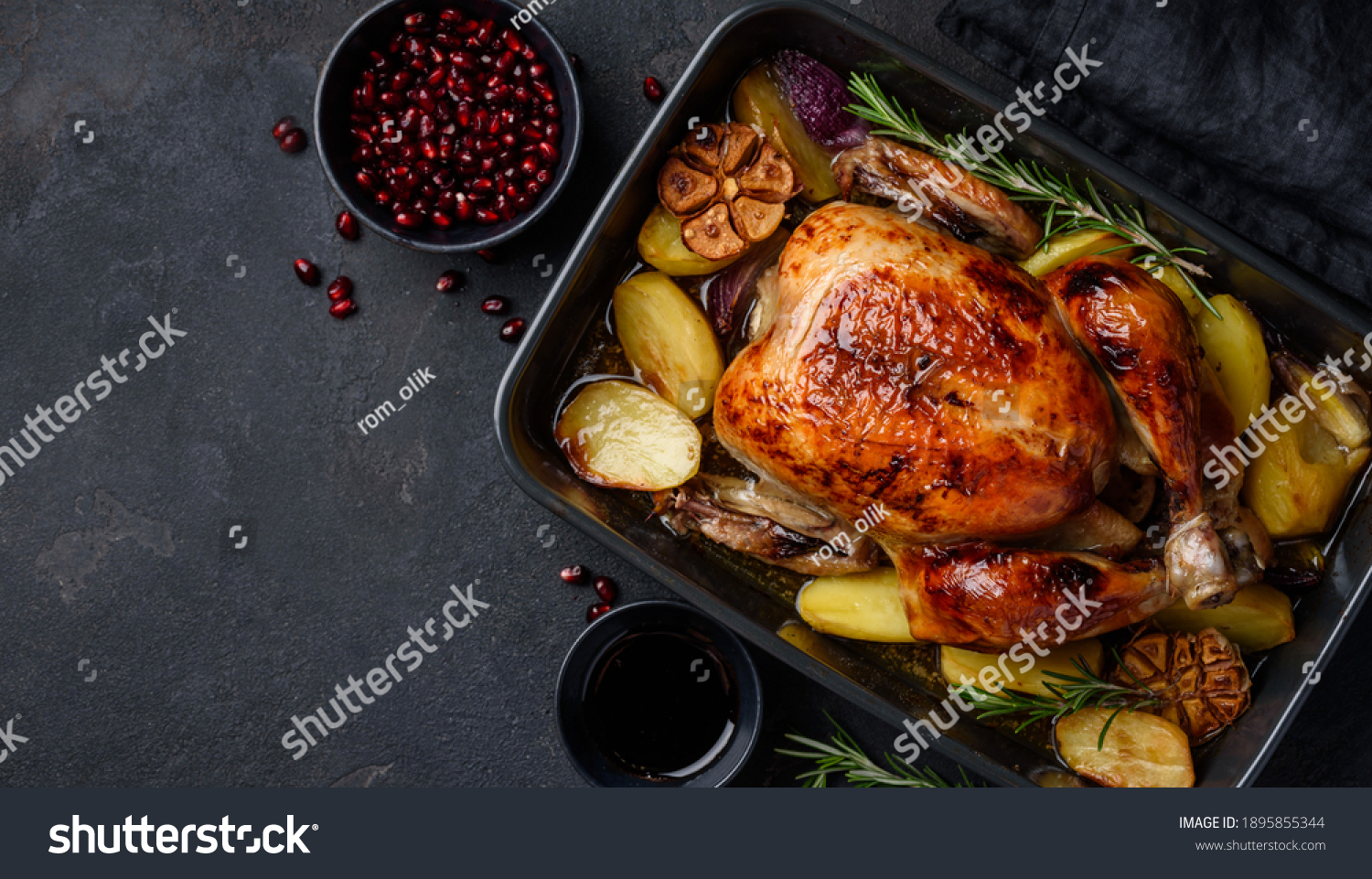 Roasted chicken in pomegranate sauce with potatoes in a gray ceramic mold. Dark background. Top view. Copy space #1895855344