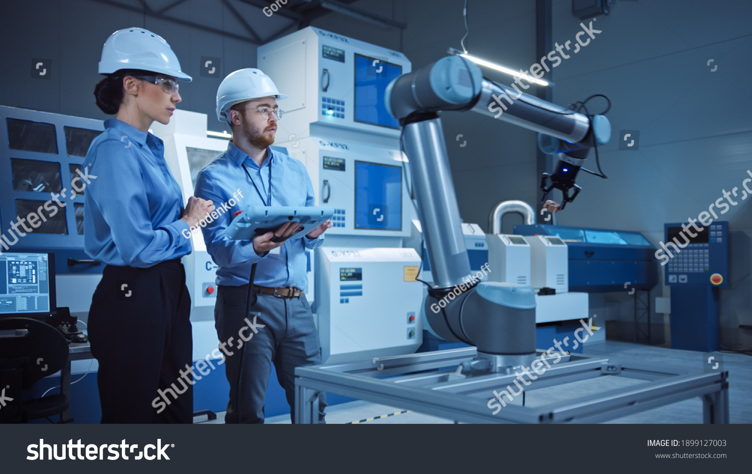 Factory Workshop: Professional Female Engineer, Male Machinery Operator Use Industrial Digital Tablet Computer to Work and Program Robot Arm for Production Line. High-Tech Facility with CNC Machines #1899127003