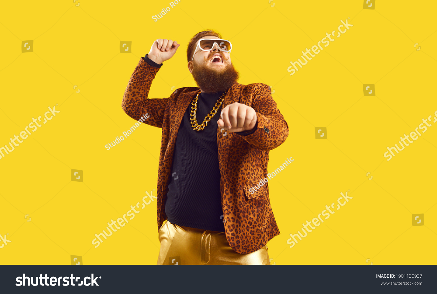 Happy funny plump young man singing songs and dancing gangnam style at a party. Funky redhead chubby guy having fun and doing rope dance move like cowboy with lasso isolated on amber color background #1901130937