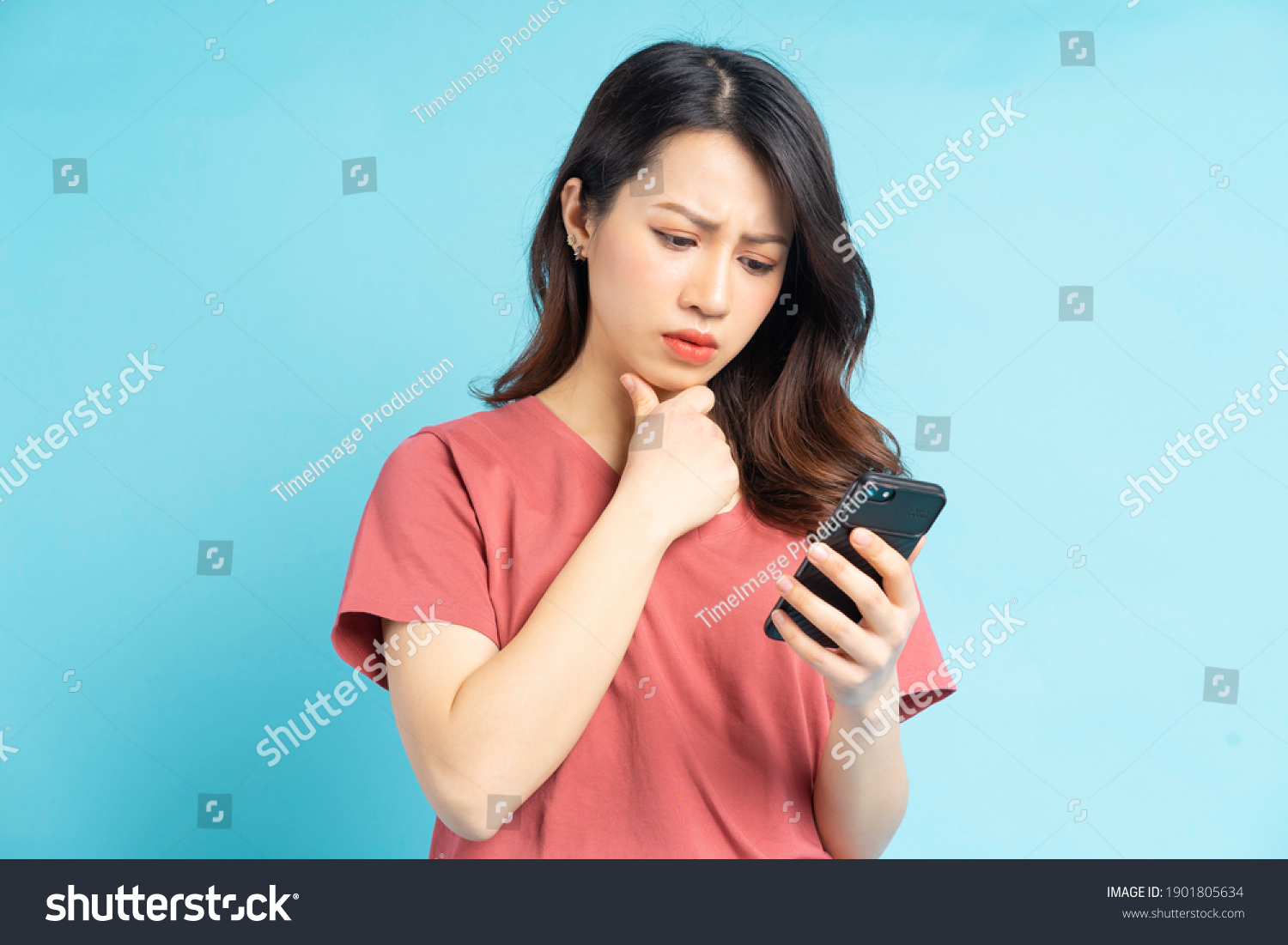 Beautiful Asian woman holding smartphone in hand with a thoughtful expression
 #1901805634
