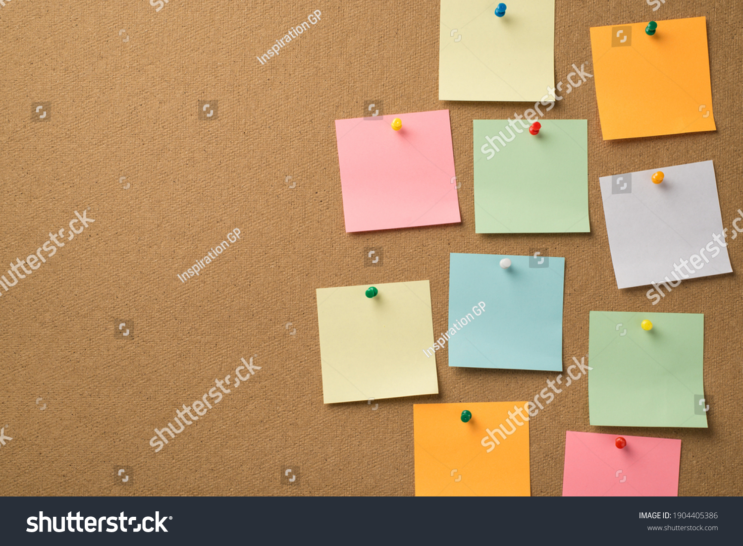 Busy day at work concept. Photo of lot of colorful notepaper attached with pins to the wooden board #1904405386