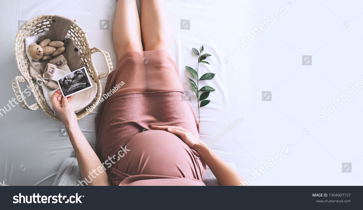 Pregnant woman in dress with ultrasound image. Mother with wicker basket of cute tiny stuff and teddy bear toy for newborn. Expectant mother waiting and preparing for baby birth during pregnancy. #1904907157