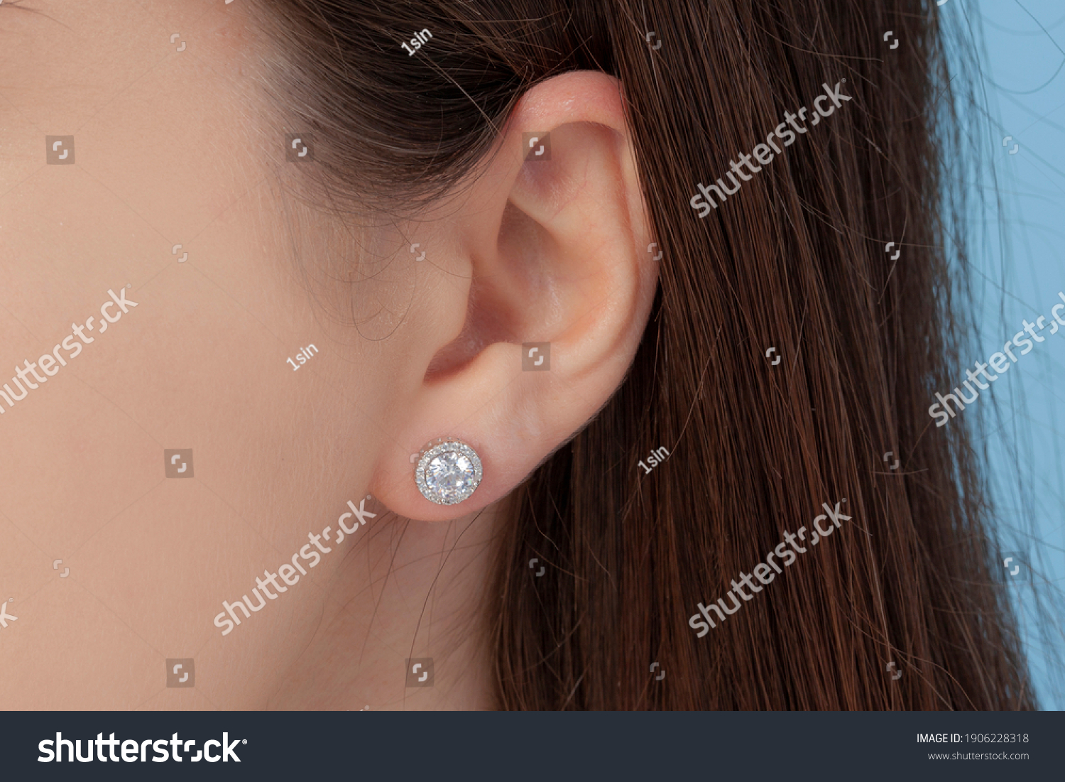 Round silver earrings on the ear of a well-groomed lady on a blue background #1906228318