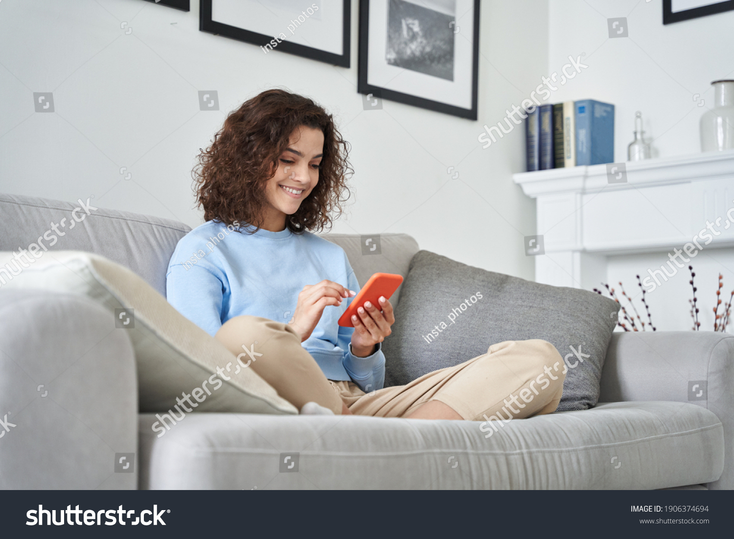 Happy hispanic teen girl holding cell phone using smartphone device at home. Smiling young latin woman blogger subscribing new social media, buying in internet, ordering products online in apps. #1906374694