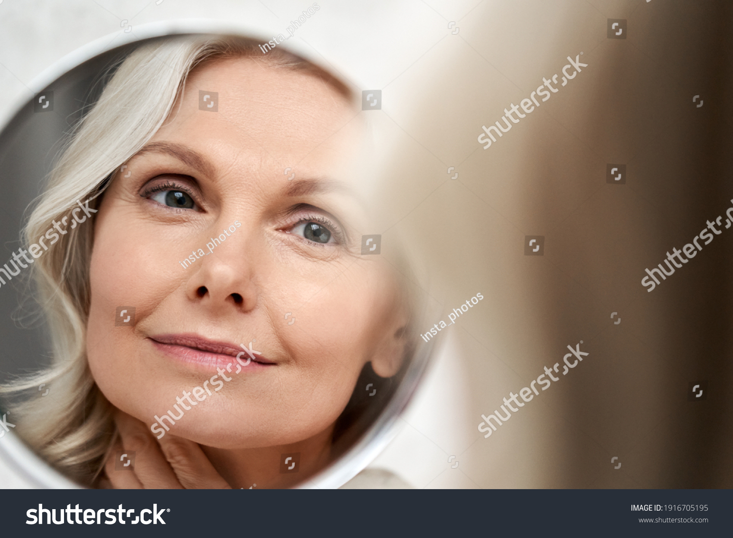 Happy 50s middle aged woman model touching face skin looking in mirror reflection. Smiling mature old lady pampering, healthy moisturized skin care, aging beauty, skincare treatment cosmetics concept. #1916705195
