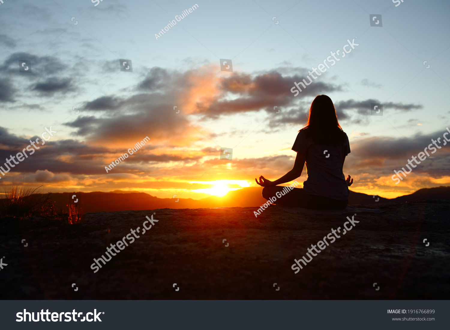 Back view portrait of a woman silhouette doing yoga at sunset in the mountain #1916766899