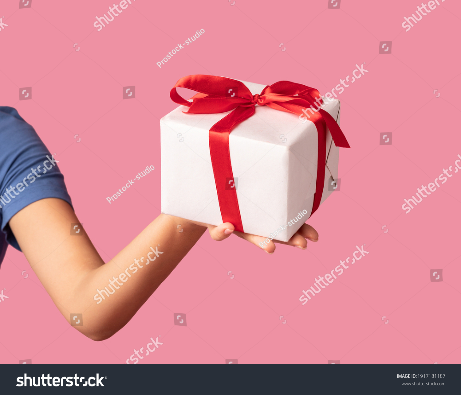 Greeting And Celebration Concept. Closeup of unrecognizable young woman holding and showing wrapped present box to camera, giving gift isolated over pastel pink studio background #1917181187