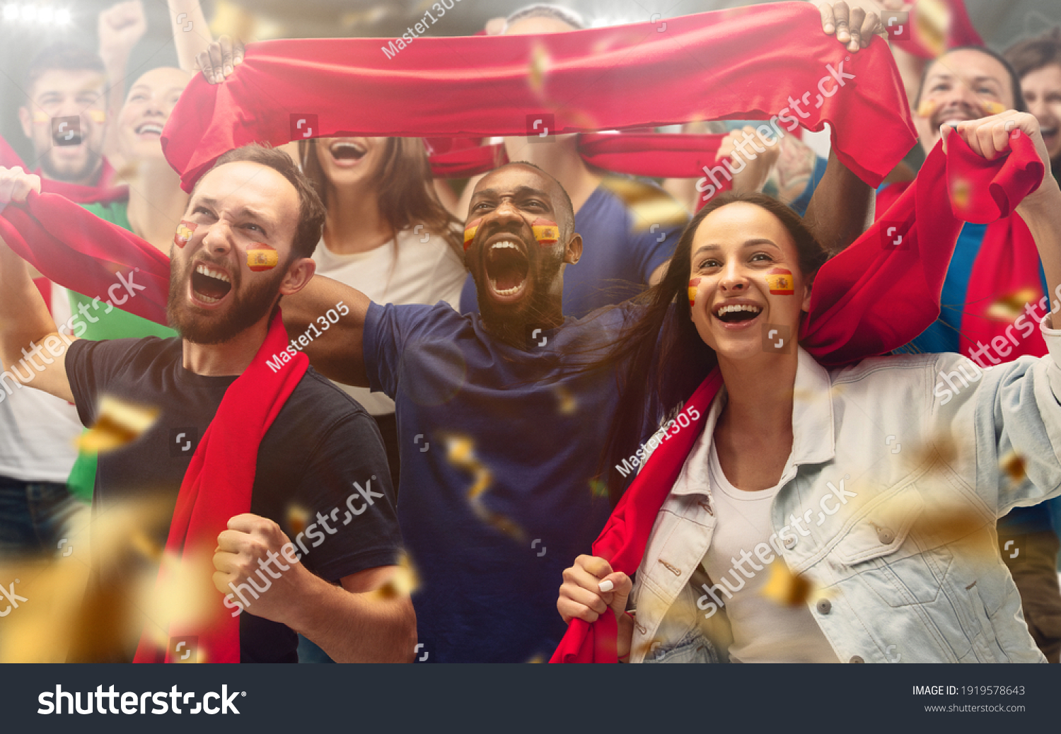 Spainian football, soccer fans cheering their team with a red scarfs at stadium. Excited fans cheering a goal, supporting favourite players. Concept of sport, human emotions, entertainment. #1919578643