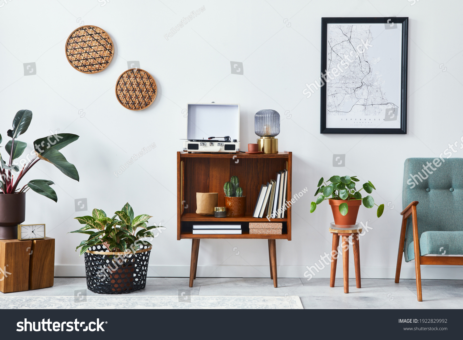 Retro composition of living room interior with mock up poster map, wooden shelf, book, armchair, plant, cacti, vinyl recorder, decoration and personal accessories in stylish home decor. #1922829992
