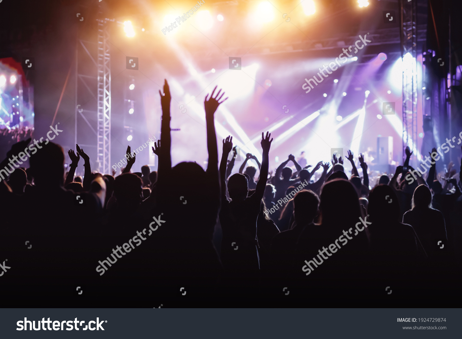 Rock concert, cheering crowd in front of bright colorful stage lights, Hands up with pleasure from the show #1924729874