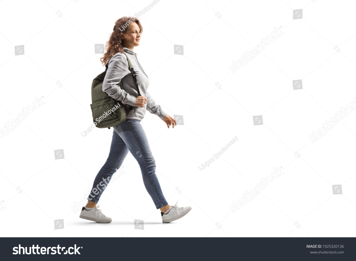Full length profile shot of a female student in jeans with a backpack walking isolated on white background #1925320136