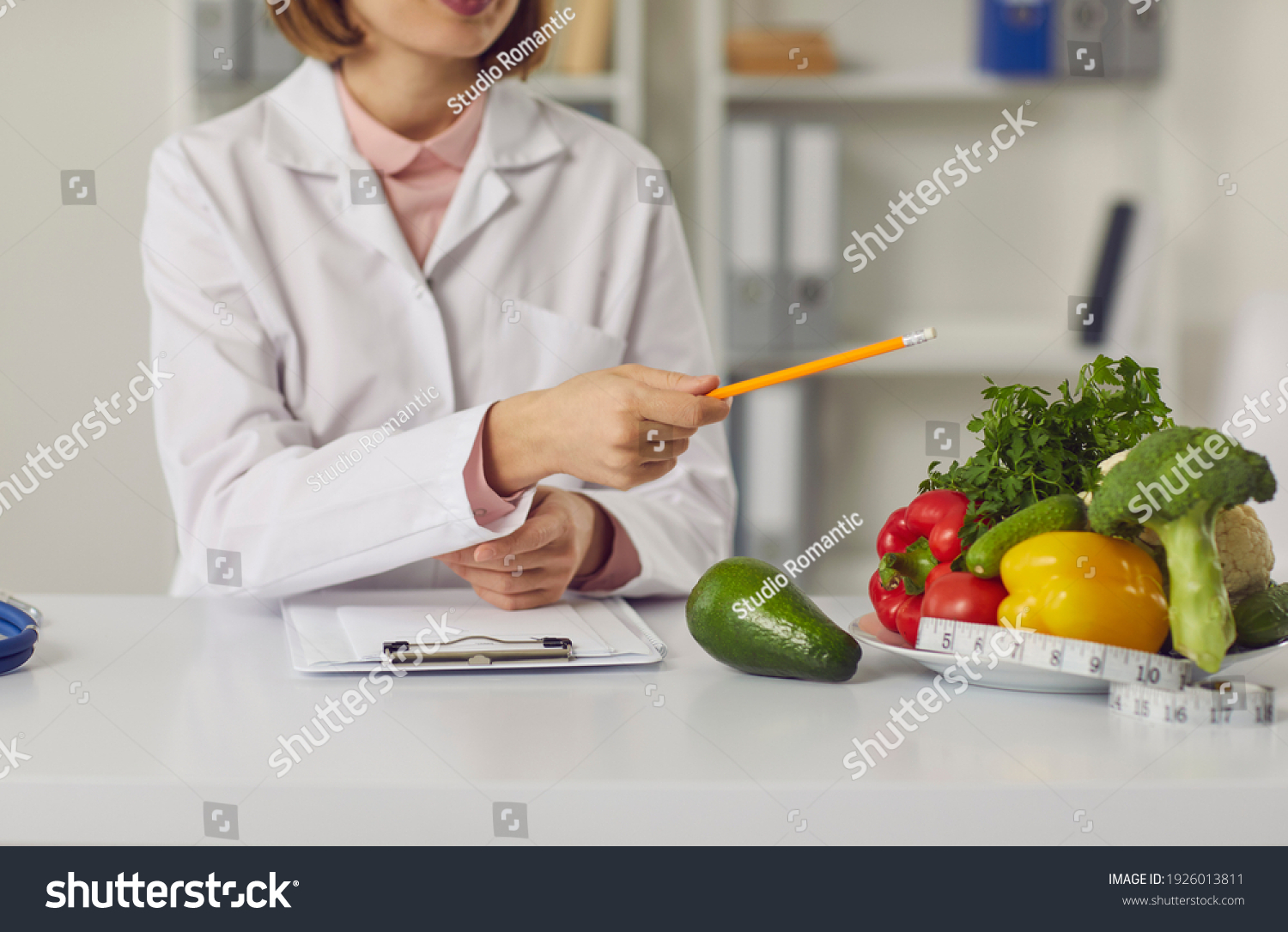 Telehealth and online nutritiologist concept. Woman doctor nutritiologist sitting and pointing at fresh vegan healthy ingredients to patient online during videocall or distant meeting #1926013811