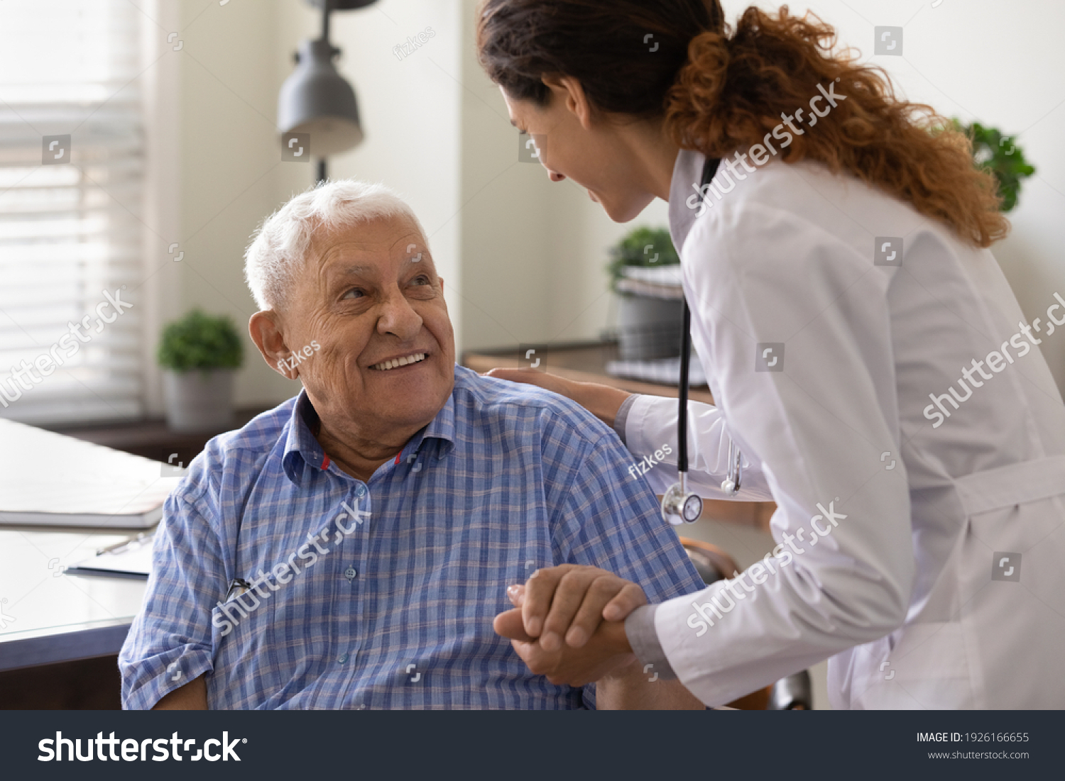 Close up caring nurse holding smiling mature patient hand at meeting in hospital, doctor caregiver wearing uniform comforting and supporting senior man, good news about treatment, empathy and care #1926166655