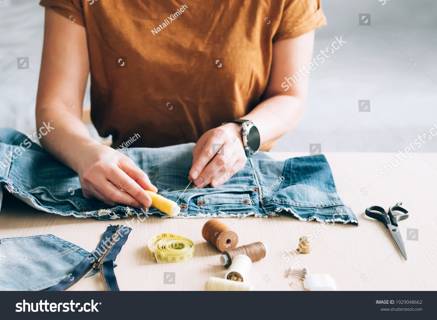 Woman repairs sews reuses fabric from old denim clothes economical reuse #1929048662