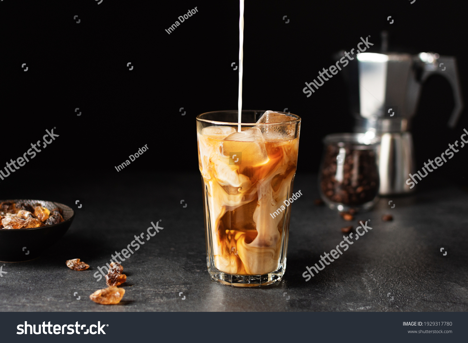 Pouring milk into a glass with iced coffee over black background. Cold refreshment summer drink. #1929317780