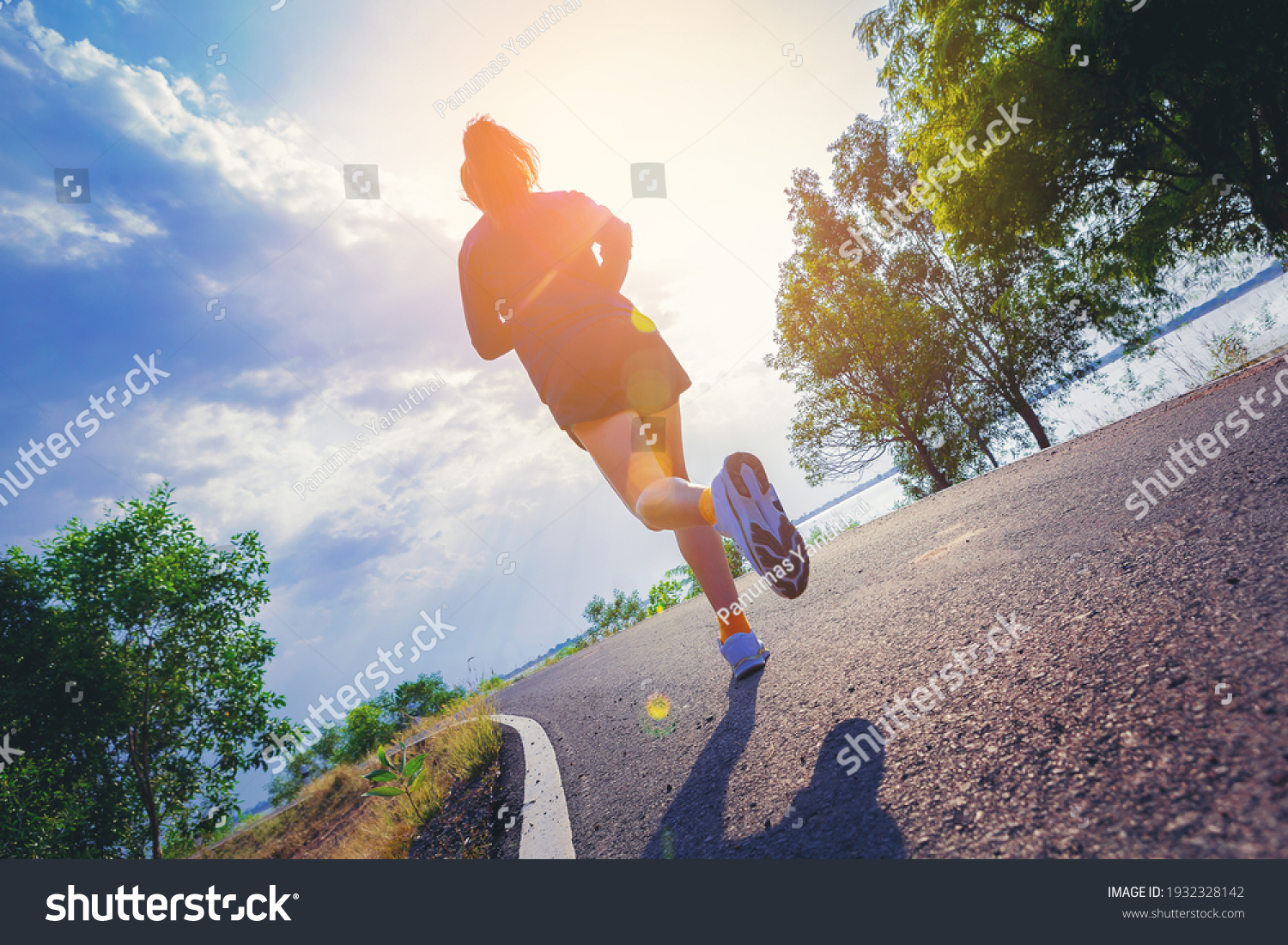 Young woman running sprinting on road. Fit runner fitness runner during outdoor workout with sunset background. #1932328142