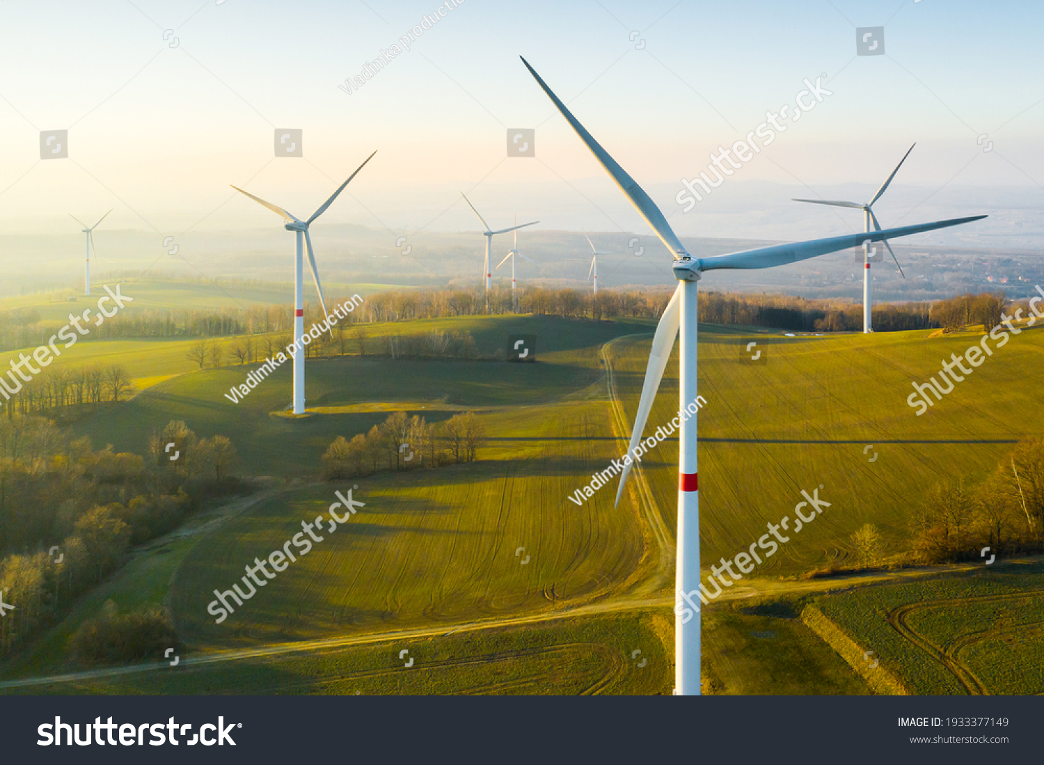 Panoramic view of wind farm or wind park, with high wind turbines for generation electricity with copy space. Green energy concept. #1933377149