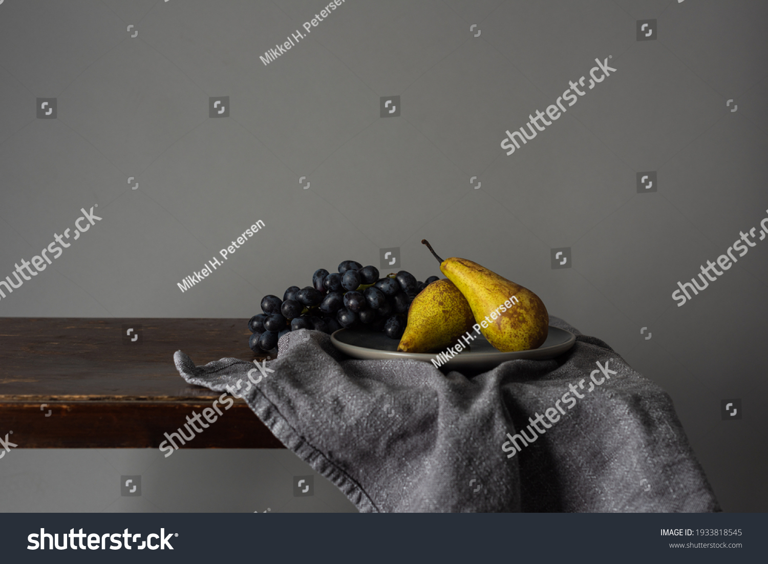 Still life with fruits. Grapes and pears on a rustic table indoors with a moody window light #1933818545