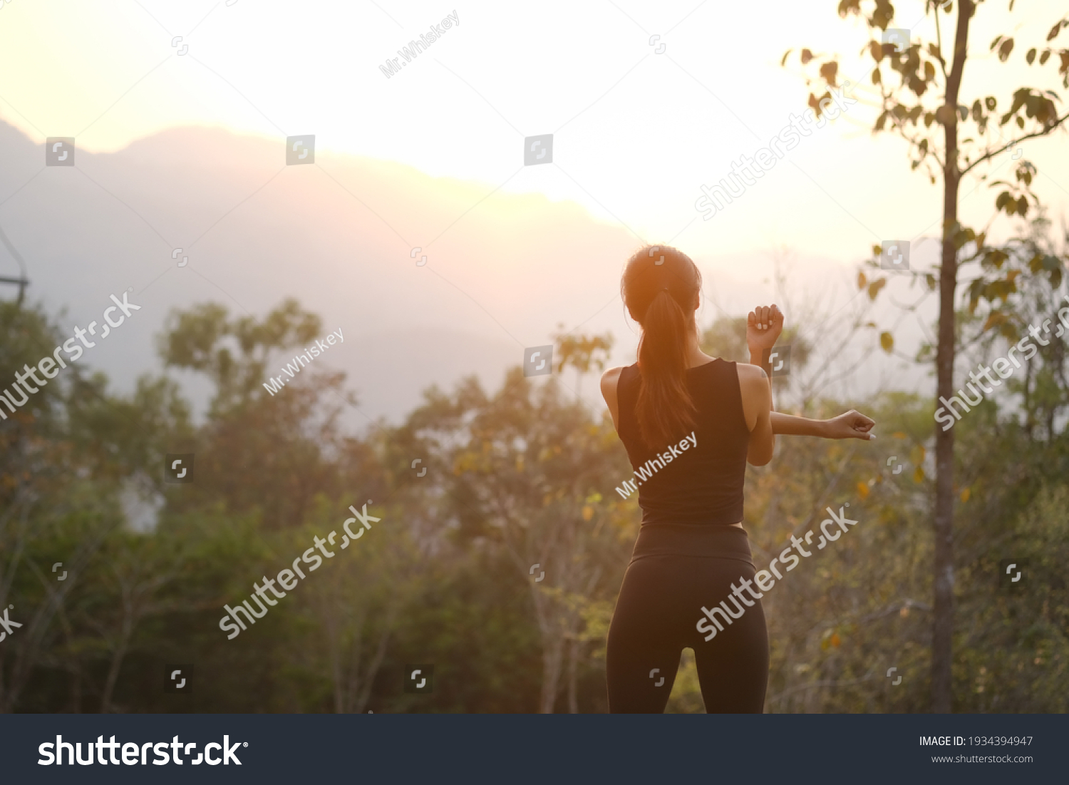 Rear view healthy young woman stretching in the park before running at the sunset. #1934394947