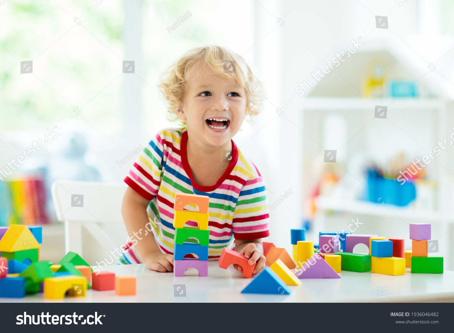 Kid playing with colorful toy blocks. Little boy building tower of block toys. Educational and creative toys and games for young children. Baby in white bedroom with rainbow bricks. Child at home. #1936046482