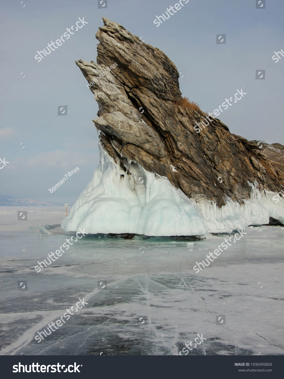 Dramatic graphical gray rock sharp texture white coastal splash ice Ogoy island Baikal lake Russia. Snow field landscape. Winter clouds overcast Visited popular innocent Tourism journey.  #1936995850