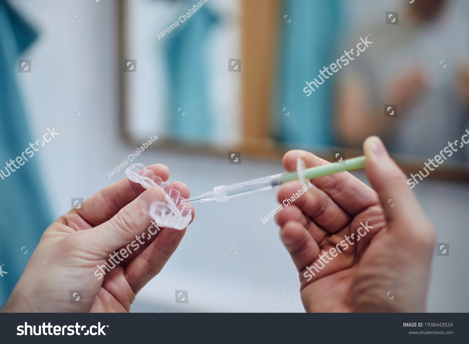 Young man preparing silicon tray for teeth whitening and bleaching gel syringe. Themes dental health, care and beauty.  #1938443524