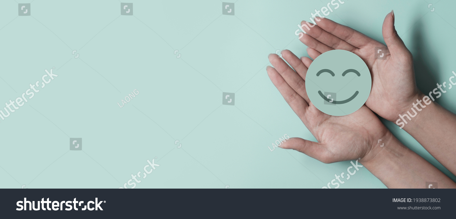 Hand holding green paper cut smile face on green background, positive thinking, mental health assessment , world mental health day concept #1938873802