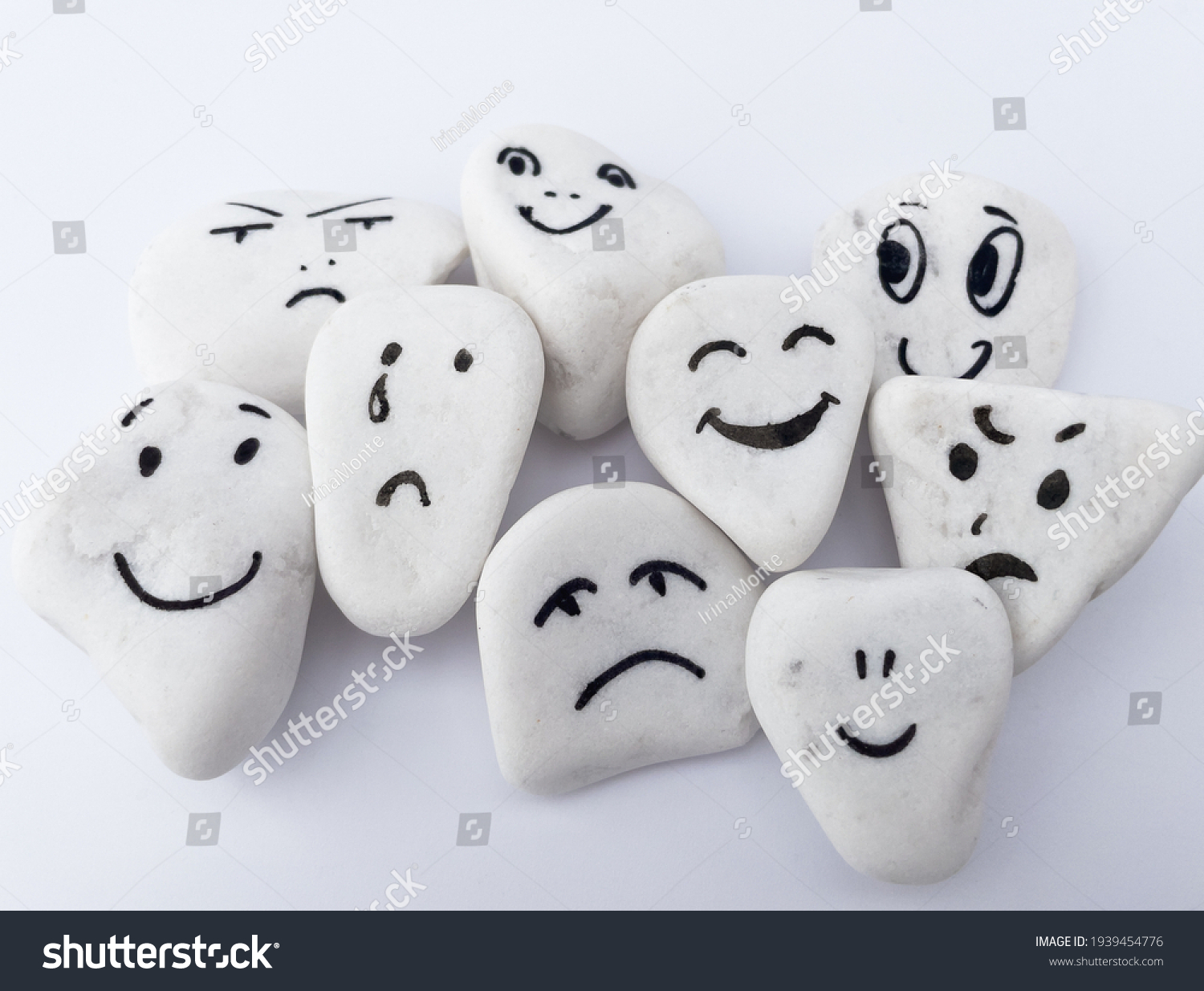 Emotion management concept, stones with painted faces symbolize different emotions. We are all different, but all together, learning to manage emotions. Soft background, white stones. #1939454776
