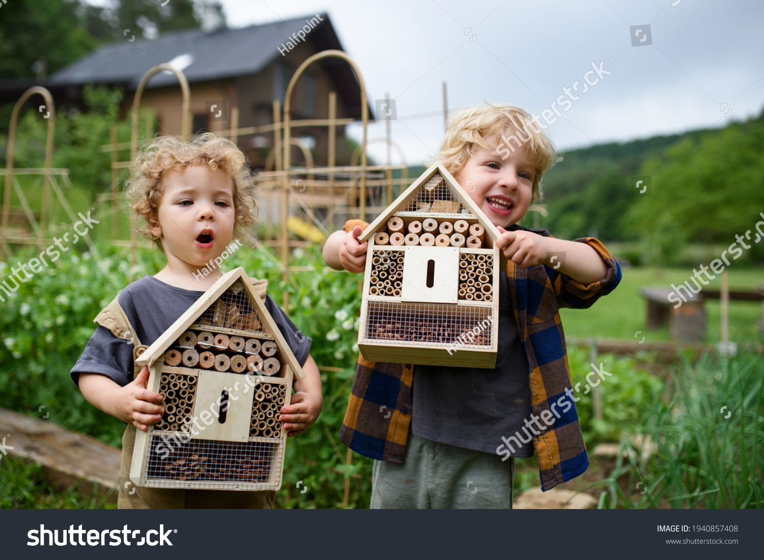 Small boy and girl holding bug and insect hotel in garden, sustainable lifestyle. #1940857408