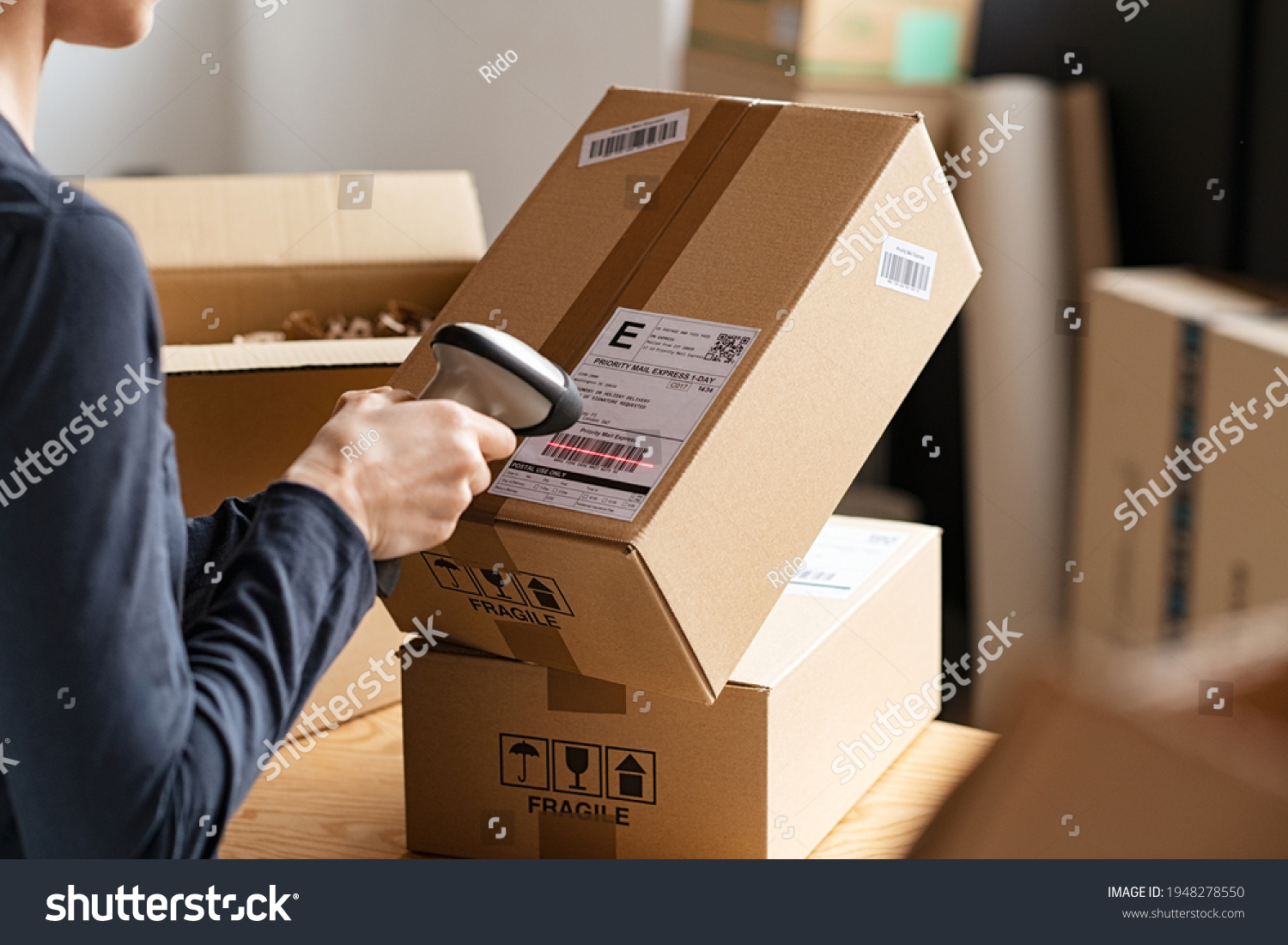 Hands scanning barcode on delivery parcel. Worker scan barcode of cardboard packages before delivery at storage. Woman working in factory warehouse scanning labels on the boxes with barcode scanner. #1948278550