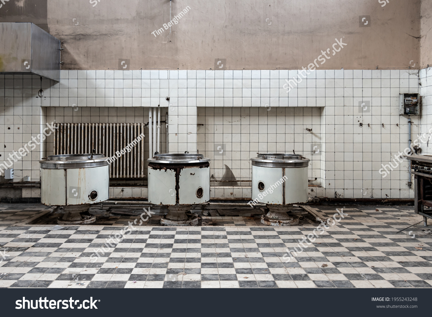 Abandoned large kitchen with 3 large cooking pots and checkerboard pattern tiles #1955243248