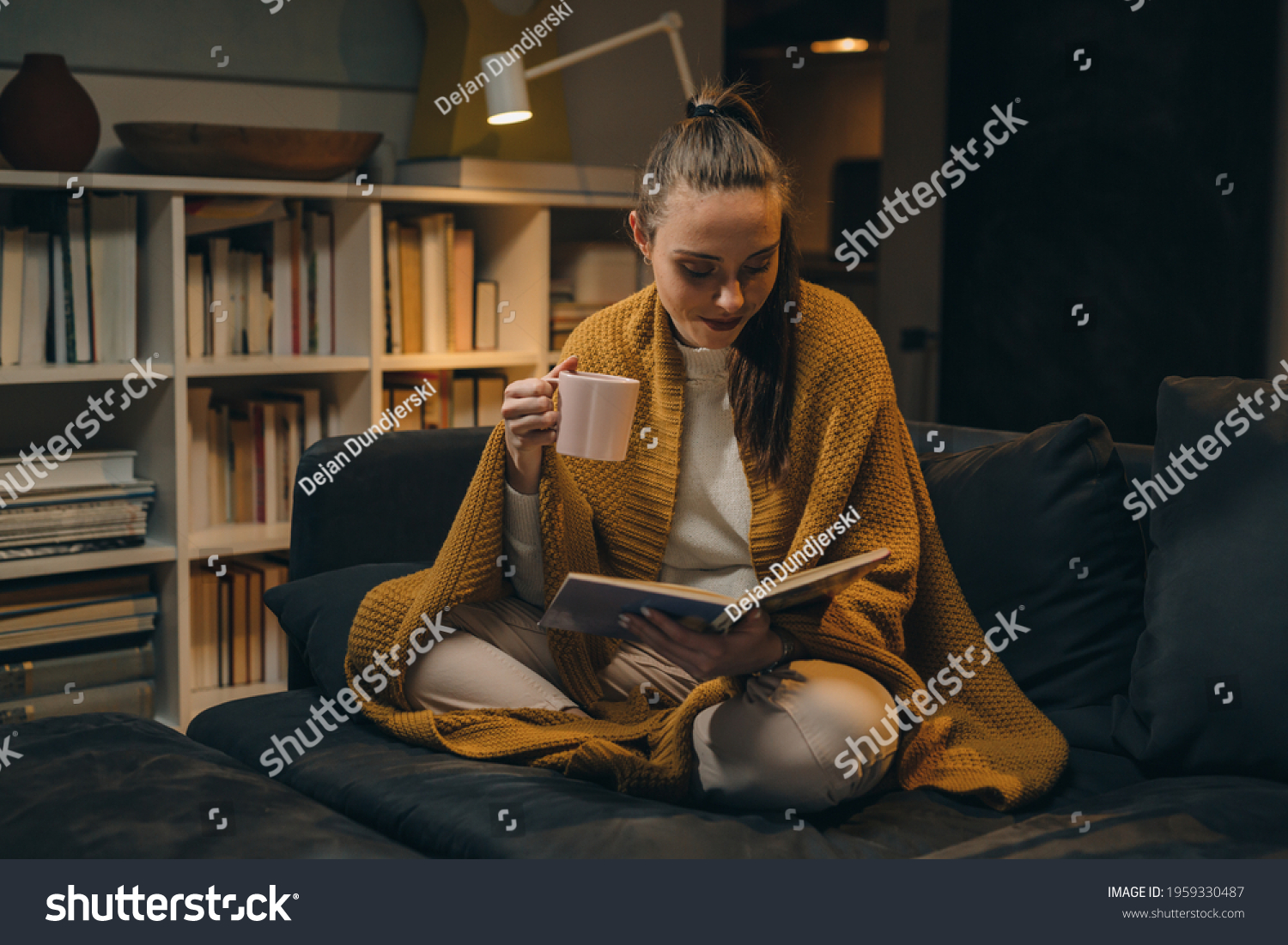 woman reading book and drinking coffee or tea at home #1959330487