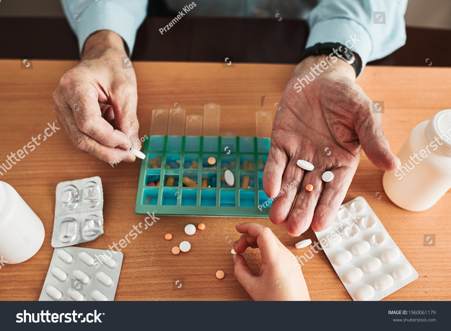 Senior man organizing his medication into pill dispenser. Senior man taking pills from box. Healthcare and old age concept with medicines. Medicaments on table #1960061179