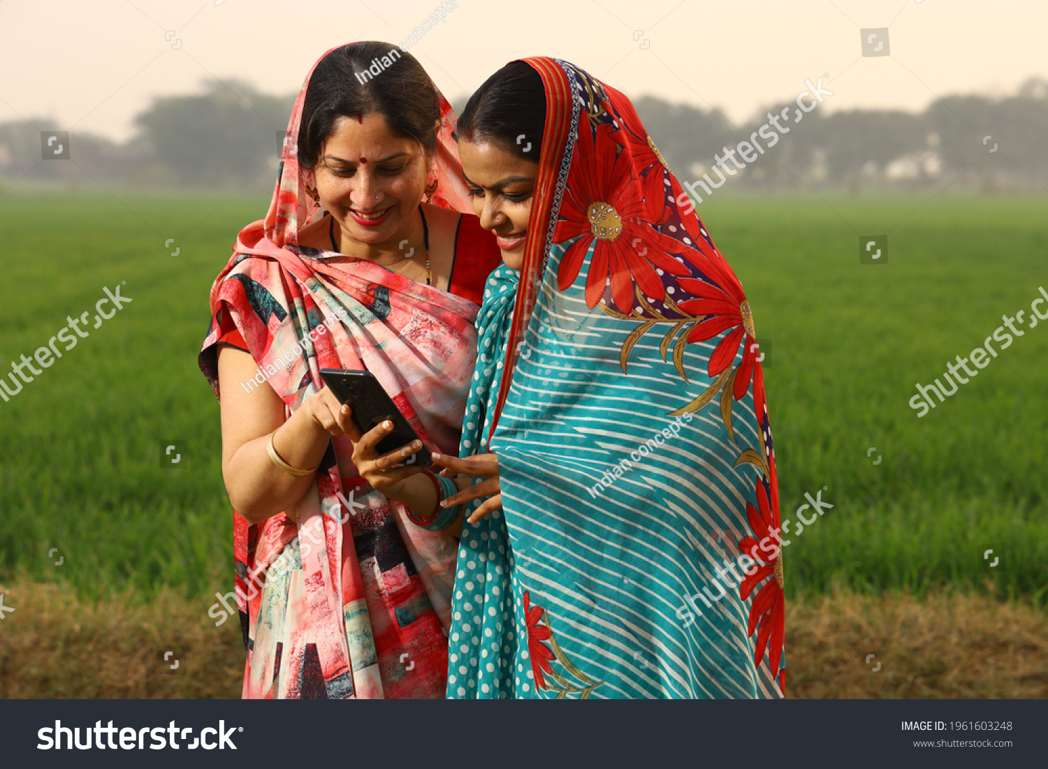 Indian rural women's looking phone in village  #1961603248