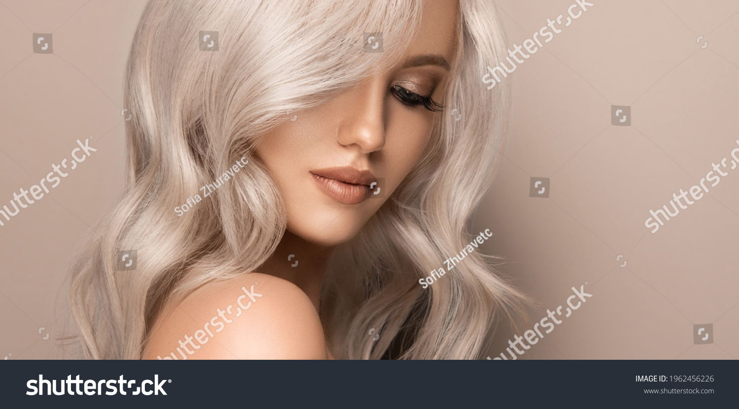 Beautiful girl with hair coloring in ultra blond. Stylish hairstyle curls done in a beauty salon. Fashion, cosmetics and makeup #1962456226