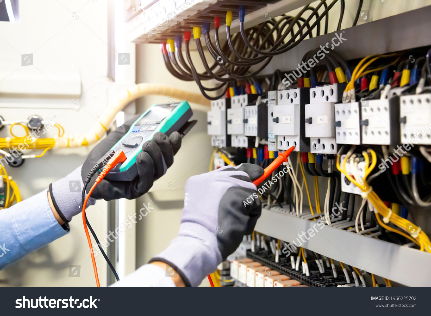 Electrical engineer using digital multi-meter measuring equipment to checking electric current voltage at circuit breaker and cable wiring system in main power distribution board. #1966225702